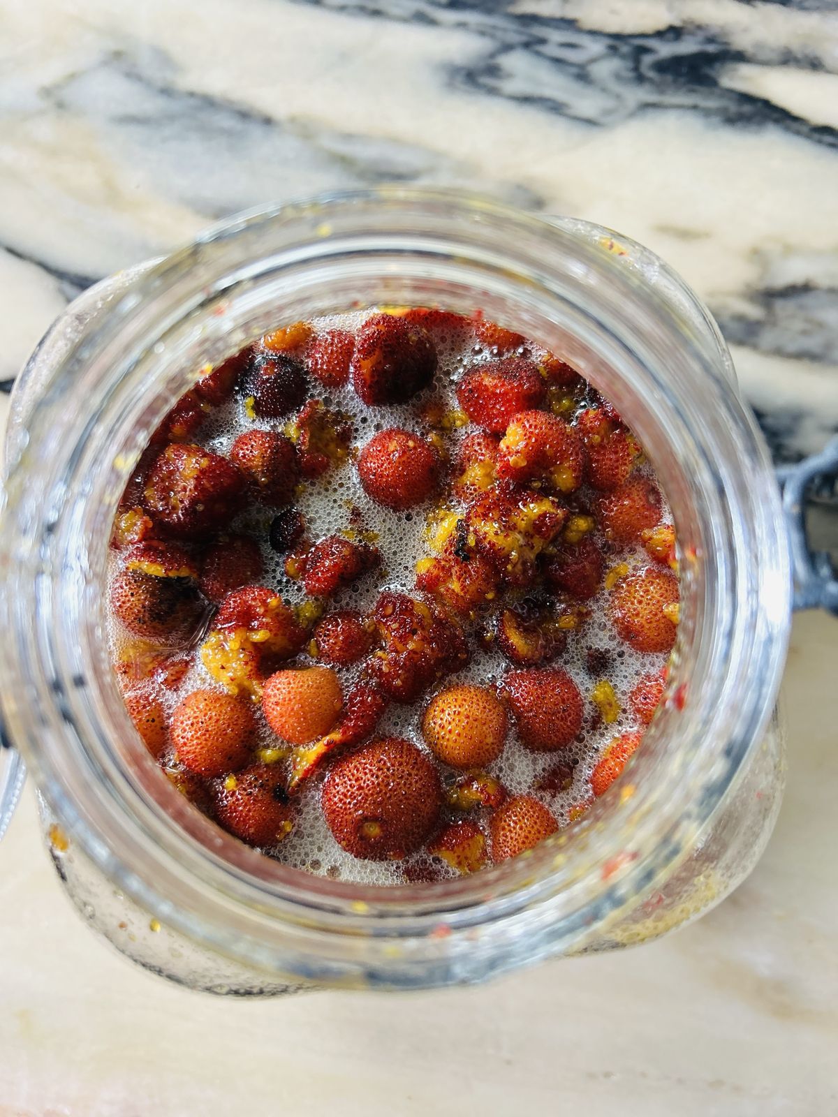 medronho fruit fermenting in a jar, seen from above